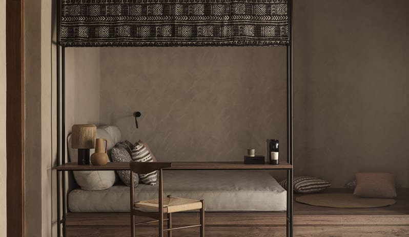 Tropical Pavilion Two Bedroom Suite with Outdoor Jacuzzi lounge and workspace in a luxury suite, featuring a built-in daybed, a dark wood desk with a woven chair, and tribal-patterned textile accents at Aulūs Lindos Rhodes, Curio Collection by Hilton by Kenwood Travel