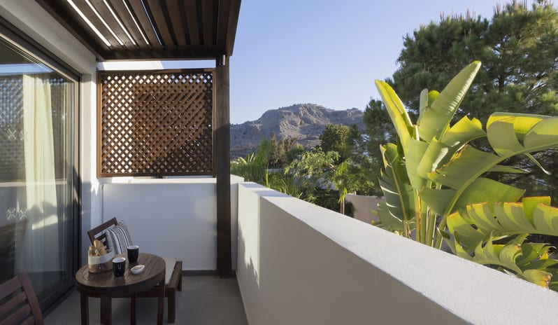 Tropical Zen Bungalow Suite Bedroom Bedroom beaturing mountain views, banana leaf plants, and contemporary wood lattice privacy screens at Aulūs Lindos Rhodes, Curio Collection by Hilton by Kenwood Travel