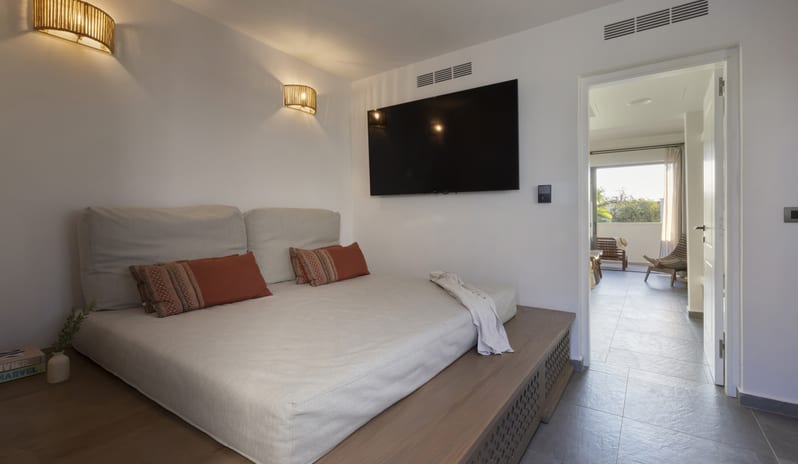 Tropical Zen Bungalow Suite Bedroom With a Canopy Bed, Stylish Rattan Lamps, and Stone Tile Flooring at Aulūs Lindos Rhodes, Curio Collection by Hilton by Kenwood Travel
