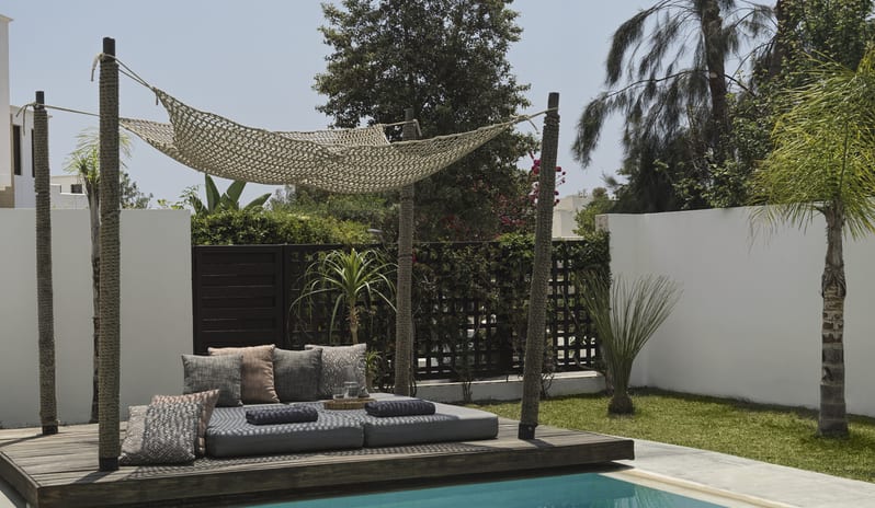 Tropical Zen Bungalow Suite with Private Pool Luxury poolside daybed on a wooden deck with plush pillows and a woven shade canopy, overlooking a private turquoise pool and tropical garden at Aulūs Lindos Rhodes, Curio Collection by Hilton by Kenwood Travel