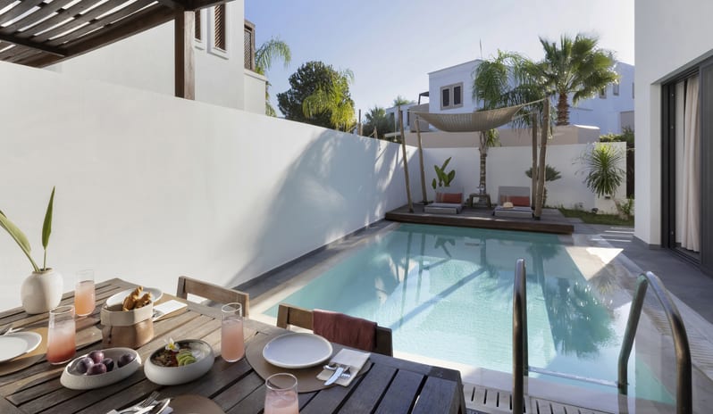 Tropical Zen Bungalow Suite with Private Pool coutdoor dining table set for breakfast, a turquoise plunge pool, and poolside lounge chairs under a shaded canopy at Aulūs Lindos Rhodes, Curio Collection by Hilton by Kenwood Travel