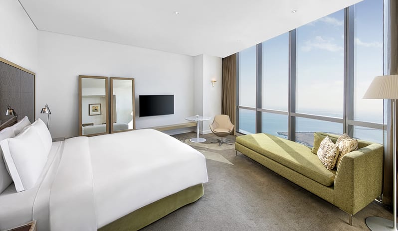 Club Room - Level 45 Bedroom Persian Gulf sea view, a green chaise lounge, and a modern workstation at Conrad Abu Dhabi Etihad Towers by Kenwood Travel