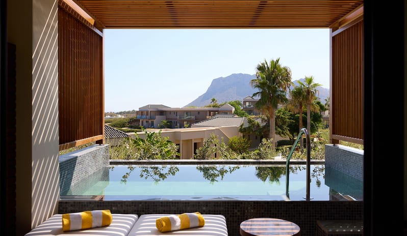 Horizon Open Plan Suite with Plunge Pool two white sun loungers with yellow striped towels, and a wooden pergola, overlooking a mountain landscape with palm trees at Aulūs Chania, Curio Collection by Hilton by Kenwood Travel