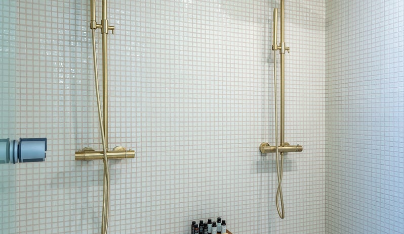 Sea View Grande Suite with Private Pool bBathroom  Dual gold rainfall shower heads, white mosaic tiling, and premium bath amenities at Aulūs Chania, Curio Collection by Hilton by Kenwood Travel