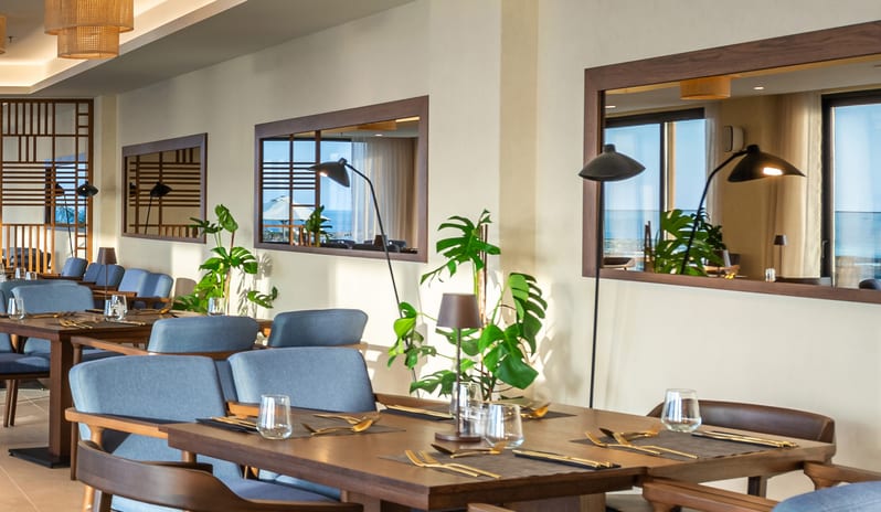 The Island Buffet Restaurant Interior view modern coastal design, rattan pendant lighting at Aulūs Chania, Curio Collection by Hilton by Kenwood Travel