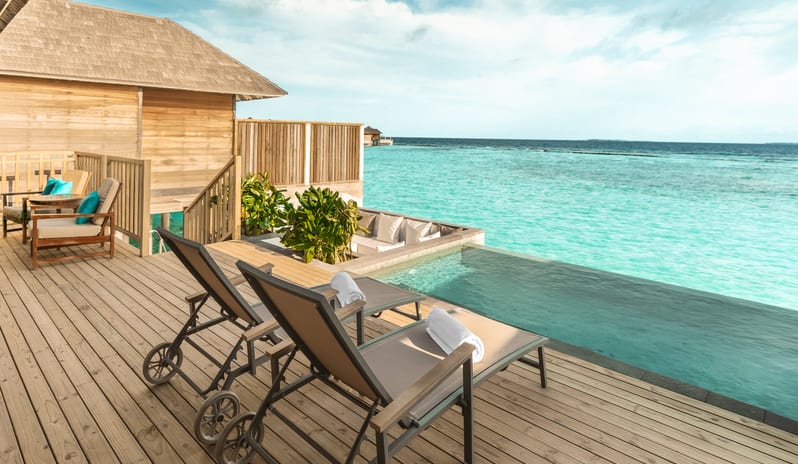Sunset Horizon Water Villa with Pool Wooden sun deck of a water villa featuring two lounge chairs, a private infinity pool, and a sunken seating area facing the bright blue ocean at Sun Siyam Iru Fushi-Sunset Horizon Water Villa with Pool  by Kenwood Travel