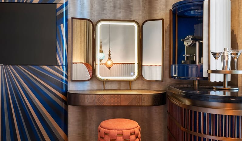 Family Corner Bedroom featuring a circular blue "MixBar" with cocktail shaker, a wooden vanity desk with a tri-fold illuminated mirror, and a textured orange ottoman at W Dubai - Mina Seyahi by Kenwood Travel