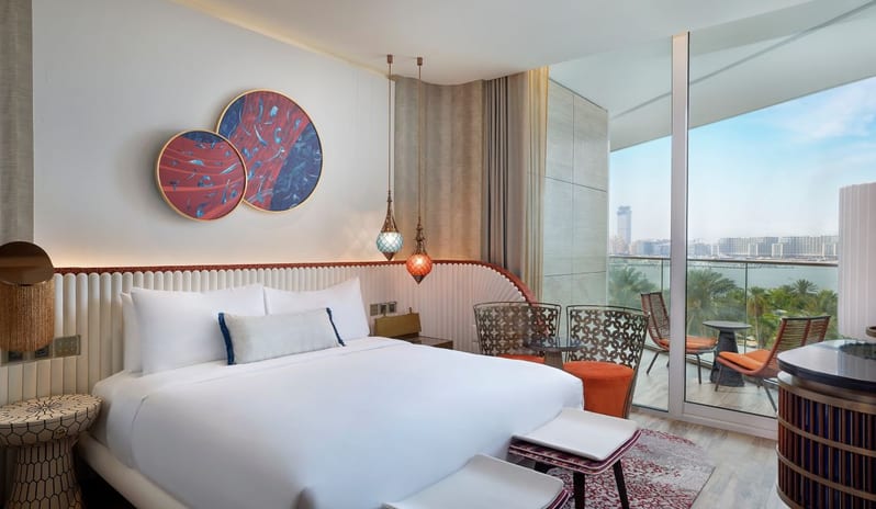 Bedroom vibrant circular wall art, hanging glass lanterns, and a private balcony overlooking the Dubai coastline at W Dubai - Mina Seyahi by Kenwood Travel