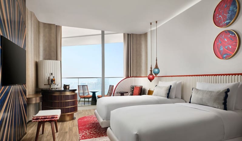 Family Suite Bedroom two beds with a fluted white headboard, a private balcony with city views, and a stylish circular mini-bar at W Dubai - Mina Seyahi by Kenwood Travel