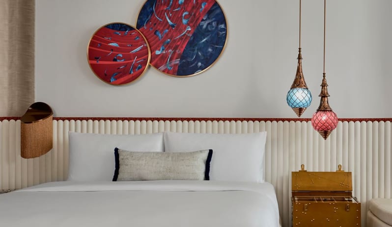 Bedroom vibrant circular wall art, hanging glass lanterns, and a private balcony overlooking the Dubai coastline at W Dubai - Mina Seyahi by Kenwood Travel