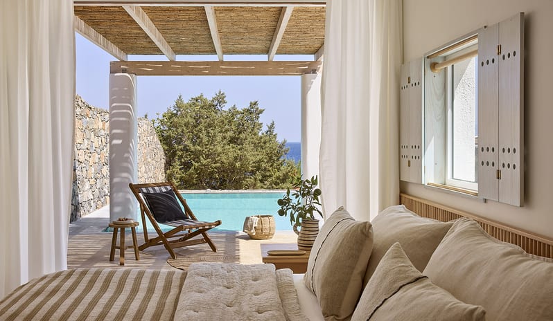 Three Bedroom Thalassa Villa Private Pool Seafront large bed with neutral-toned linens, opening directly onto a private poolside terrace with an ocean view in Greece at St.Nicolas Bay Resort by Kenwood Travel