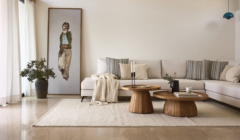 Three Bedroom Thalassa Villa Private Pool Seafront neutral sectional sofa, twin wooden pedestal coffee tables, a large figurative art piece, and bright, sunlit windows with cream curtains at St.Nicolas Bay Resort by Kenwood Travel