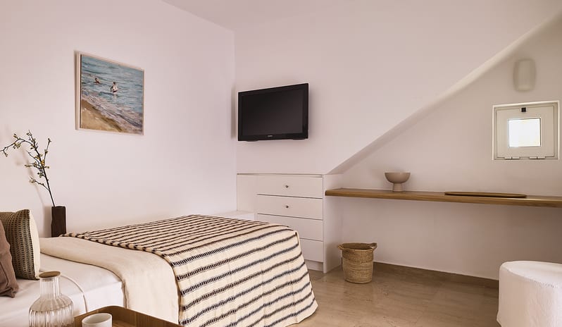 Three Bedroom Thalassa Villa Private Pool Seafront minimalist white decor, a wall-mounted TV, built-in dresser, and a bed with a textured neutral-toned throw at St.Nicolas Bay Resort by Kenwood Travel