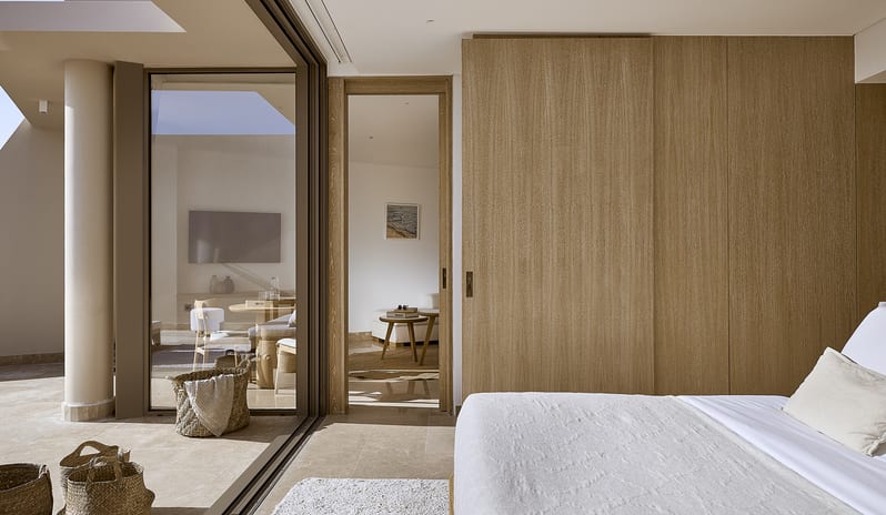 Olives & Sea 3-Bedroom Villa Private Pool Harbour View/Sea View sliding glass doors opening to a sunlit terrace, natural wood wardrobe, and woven basket decor with a view into the living area at St.Nicolas Bay Resort by Kenwood Travel