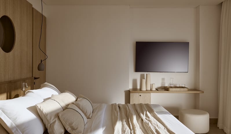 Olives & Sea 3-Bedroom Villa Private Pool Harbour View/Sea View warm wood paneling, a wall-mounted flat-screen TV, floating desk, and luxury linens in neutral tones at St.Nicolas Bay Resort by Kenwood Travel