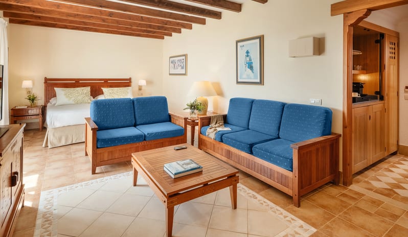 Double Superior Relax hotel room with wood beam ceilings, large flat-screen TV on a wooden console, and a comfortable blue lounge chair at Princesa Yaiza Suite Hotel Resort by Kenwood Travel