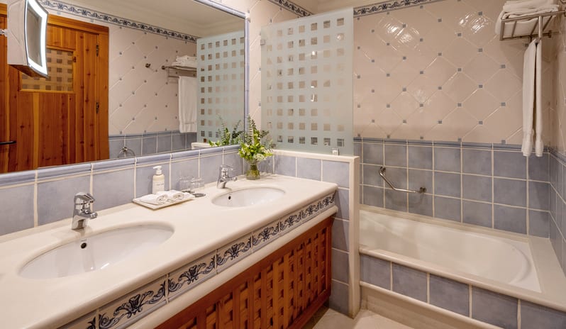 Bathroom double vanity sink with wooden cabinetry, blue and white Mediterranean tiles, a walk-in shower, and a separate bathtub Princesa Yaiza Suite Hotel Resort by Kenwood Travel