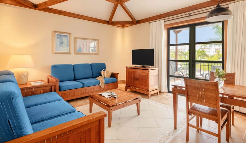 Suite Relax living area with two blue sofas, a dining table, and large glass doors opening onto a balcony with a tropical view at Princesa Yaiza Suite Hotel Resort by Kenwood Travel