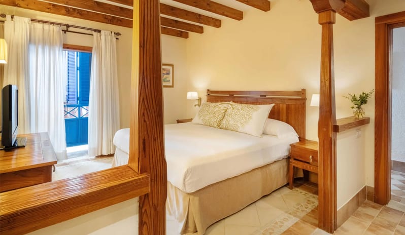 Suite Relax bedroom featuring exposed wooden ceiling beams, a large bed with white linens, and warm ambient lighting at Princesa Yaiza Suite Hotel Resort by Kenwood Travel
