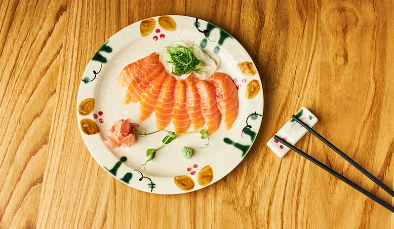 A plate of fresh salmon sashimi served with seaweed salad, ginger, and wasabi at Princesa Yaiza Suite Hotel Resort in Europe Holidays by Kenwood Travel