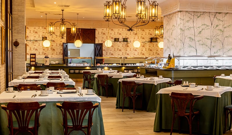Main dining area of La Piazzetta featuring elegant chandeliers, floral wallpaper, and green table linens at Princesa Yaiza Suite Hotel Resort in Europe Holidays by Kenwood Travel