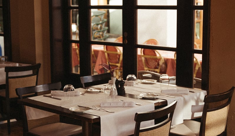 Elegant indoor table setting at Don Giovanni featuring a large arched window and wooden floors at Princesa Yaiza Suite Hotel Resort in Europe Holidays by Kenwood Travel