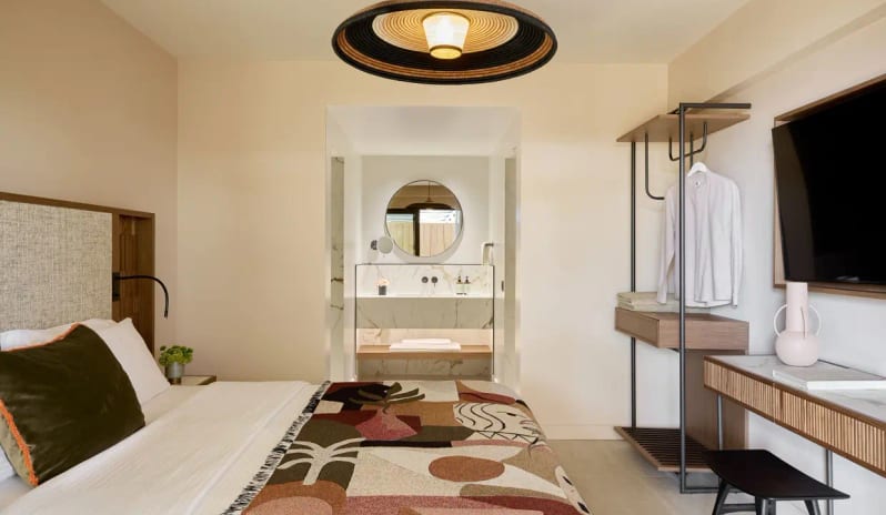 Two Bedroom Suite Sea View king bed with earth-toned patterned throw, minimalist open wardrobe, and an en-suite marble bathroom vanity at Eagles Palace by Kenwood Travel