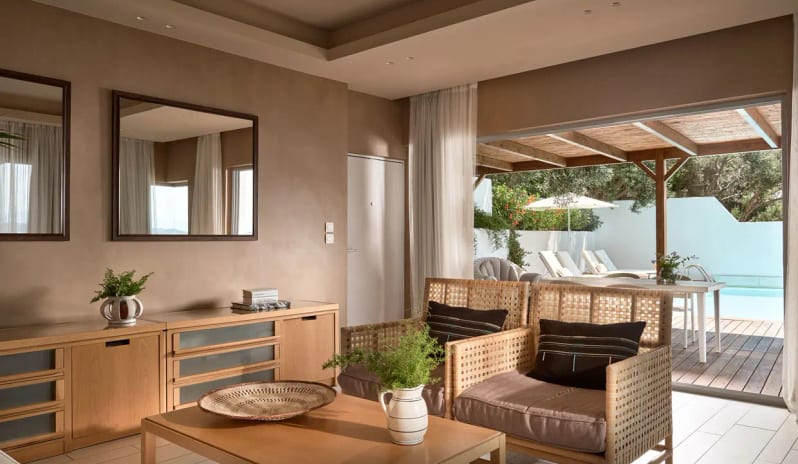 Presidential Bungalow two woven armchairs, a glass coffee table with green apples, a flat-screen TV, and two large square mirrors on a neutral wall at Eagles Palace by Kenwood Travel