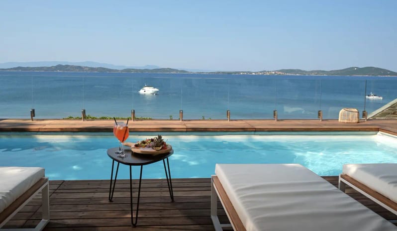 Presidential Bungalow turquoise swimming pool, white sun loungers, and a wooden pergola-shaded dining area with white wicker armchairs at Eagles Palace by Kenwood Travel