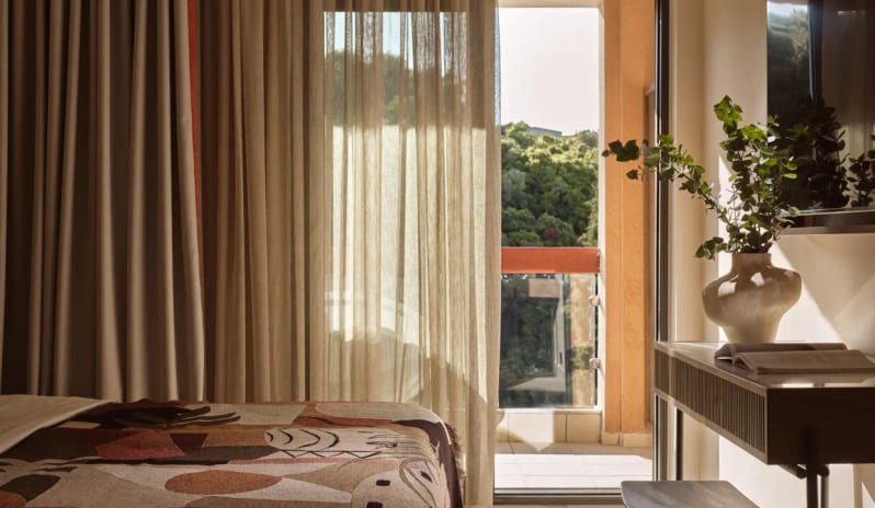 Deluxe Double Room Garden View private balcony with garden views, featuring sun-drenched sheer curtains and a designer bed throw at Eagles Palace by Kenwood Travel