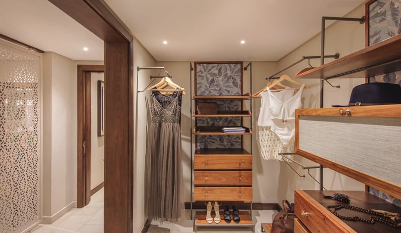 Palm Suite organized walk-in closet in a high-end suite featuring custom wood drawers, open shelving, and hanging space at Royal Palm Beachcomber Luxury by Kenwood Travel