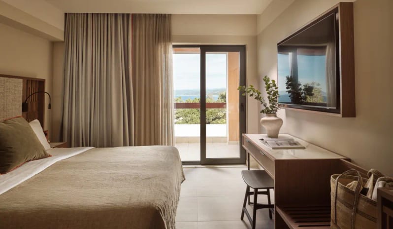 Deluxe Double Room Sea View Bed room with sea view balcony, minimalist wood furniture, and flat-screen TV at Eagles Palace by Kenwood Travel