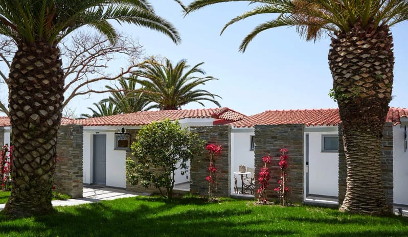Bungalow Garden View Luxury white-walled bungalow with red tile roof surrounded by palm trees and bougainvillea in a lush green garden setting. at Eagles Palace by Kenwood Travel