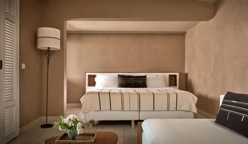 Bungalow Sea Front earth-toned walls, a white king-size bed with striped linens, and a tall wrought-iron floor lamp at Eagles Palace by Kenwood Travel