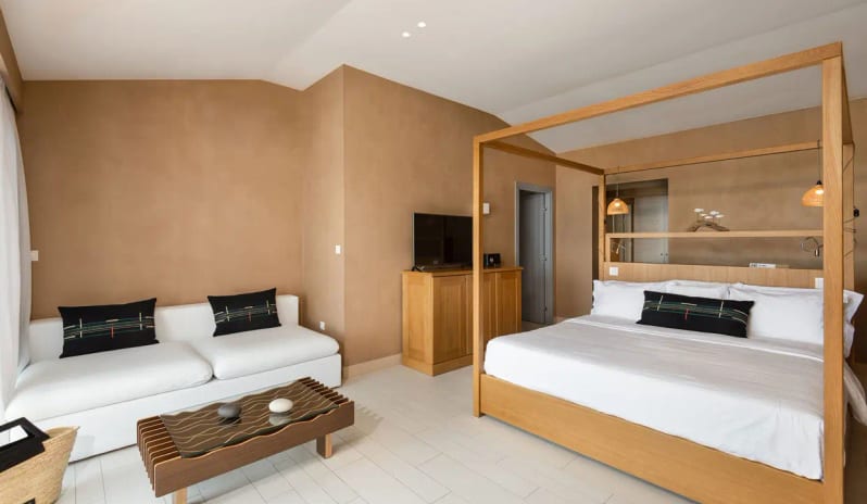 Bungalow Sea View light wood canopy bed, white sofa, and earthy textured walls at Eagles Palace by Kenwood Travel