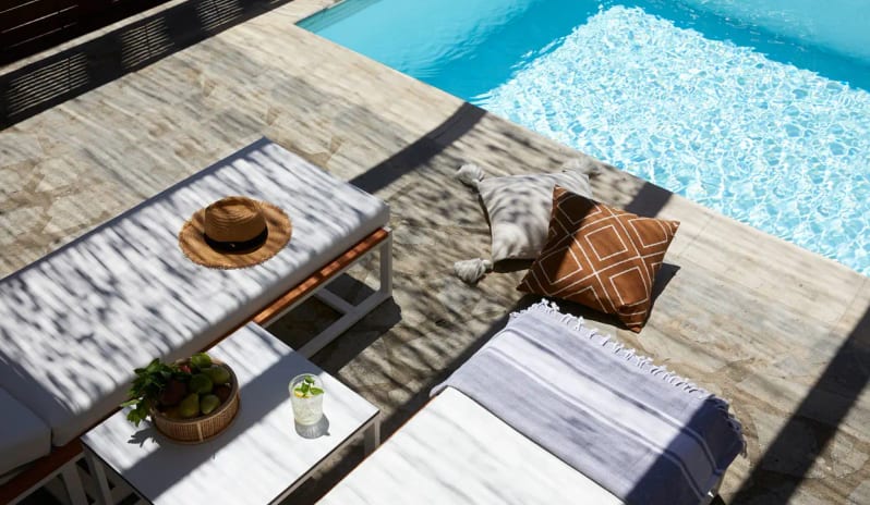 Two Bedroom Suite Garden View Private Pool open-plan living room with blue sofas, a dining area, and a white arched transition leading to a private garden terrace at Eagles Palace by Kenwood Travel