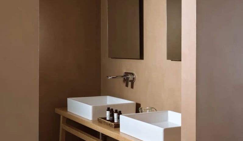 Bungalow Sea View bathroom double white vessel sinks, a wooden vanity, and sleek wall-mounted fixtures against warm ochre walls at Eagles Palace by Kenwood Travel