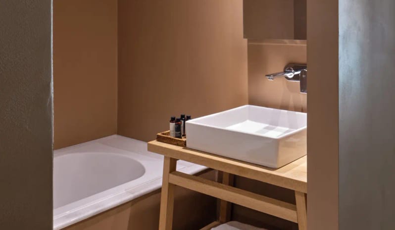 Bungalow Garden View bathroom white vessel sink on a wooden vanity, a deep soaking tub, and warm earth-toned walls at Eagles Palace by Kenwood Travel