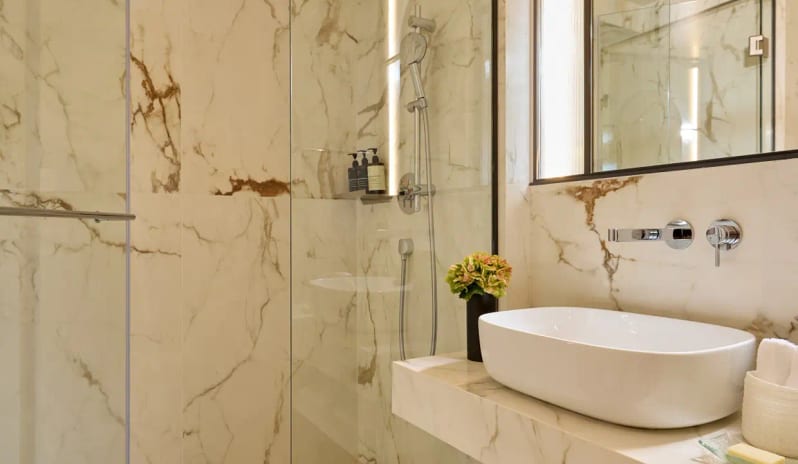 Deluxe Double Room Sea View Bathroom floor-to-ceiling marble tiles, a white vessel sink, and a glass-enclosed walk-in rain shower at Eagles Palace by Kenwood Travel