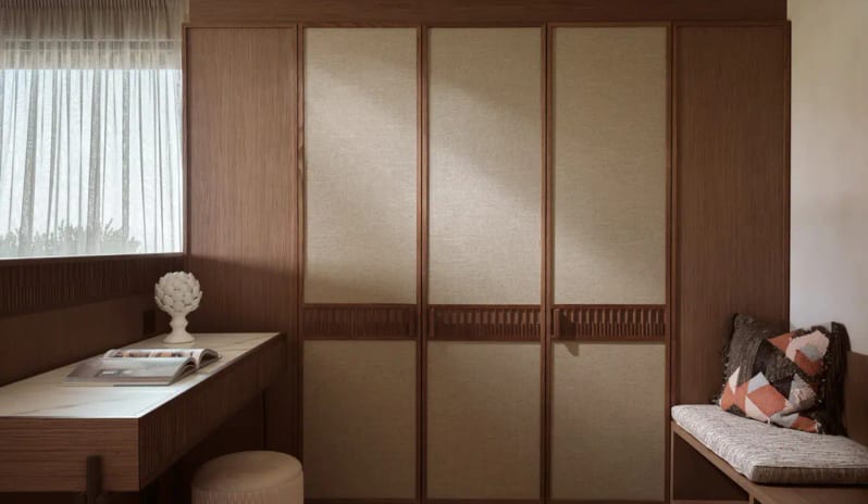 Deluxe Junior Suite Sea View fLuxury suite dressing area featuring floor-to-ceiling wooden wardrobes with linen fabric inlays, a marble-top vanity desk, and a cushioned bench with decorative pillows at Eagles Palace by Kenwood Travel