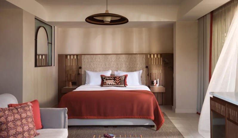 Deluxe Junior Suite Sea View king bed with terracotta linens, textured wood headboard, a modern pendant light, and a private balcony view at Eagles Palace by Kenwood Travel