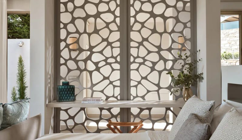 Junior Pool Villa Sea View bedroom decor at Eagles Resort, showing a unique grey geometric room divider, natural lighting, and elegant interior styling in Greece at Eagles Villas by Kenwood Travel