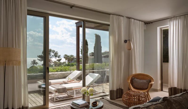 Junior Pool Villa Sea View Mediterranean interior design in a luxury Greek villa, showcasing wicker furniture, neutral tones, and a bright terrace overlooking the Aegean coast at Eagles Villas by Kenwood Travel