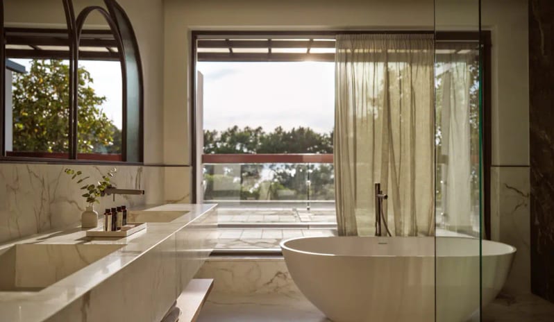 Panorama Suite Sea Front large freestanding soaking tub, a double marble vanity, and a balcony view through floor-to-ceiling windowsat Eagles Palace by Kenwood Travel