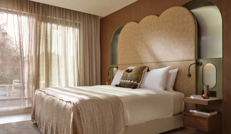 Panorama Suite Sea Front bedroom in the Panorama Suite at Eagles Resort Halkidiki, featuring a unique scalloped headboard and warm earth tones at Eagles Palace by Kenwood Travel