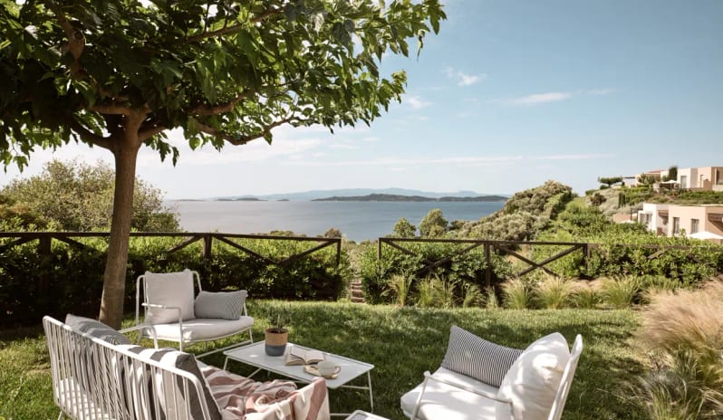 Residential 3 Bedroom Pool Villa Private Garden Sea View white outdoor lounge set under a shade tree, overlooking the turquoise Aegean Sea and distant islands at Eagles Villas by Kenwood Travel