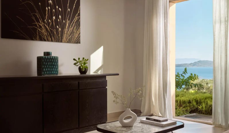 Residential 3 Bedroom Pool Villa Private Garden Sea View featuring a dark wood console, minimalist ceramics, and a view through a sunlit doorway to the turquoise Aegean Sea by Kenwood Travel