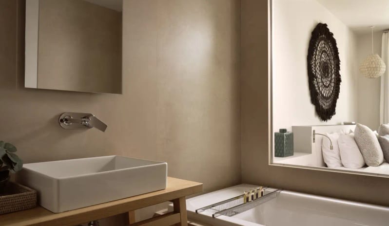 Residential 3 Bedroom Pool Villa Private Garden Sea View bathroom featuring a square vessel sink on a wooden vanity and a bathtub, with a large mirror reflecting the adjacent bedroom's woven decor at Eagles Villas by Kenwood Travel