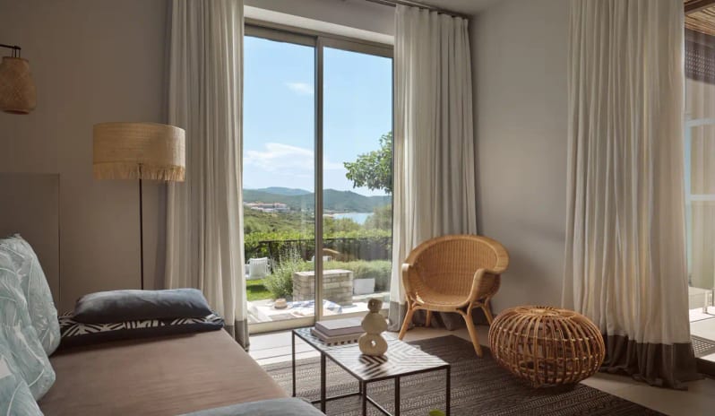 Residential 2 Bedroom Pool Villa Private Garden Sea View twicker furniture, a sliding glass door opening to a private landscaped garden, and a view of the Mediterranean coastline at Eagles Villas by Kenwood Travel