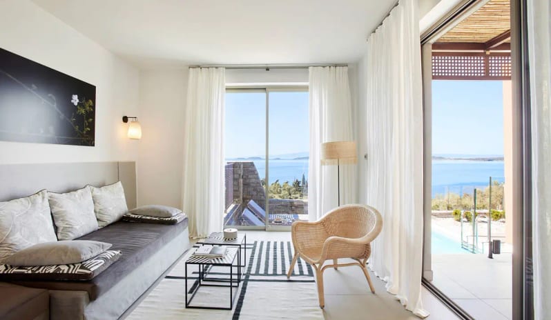 Residential 2 Bedroom Pool Villa Sea View Elegant villa bedroom at Eagles Resort Halkidiki featuring two vertical windows with a deep blue sea view, white louvered wardrobes, and a minimalist bedside table at Eagles Villas by Kenwood Travel